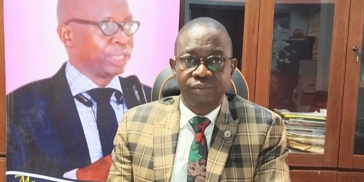 A man sitting indoor, in a well lit room. Wearing glasses and putting on suit