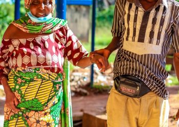A woman walking in an hospital environment and a young man holding her hand
