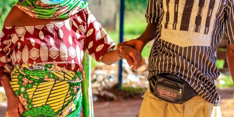 A woman walking in an hospital environment and a young man holding her hand