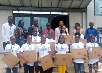 People standing out door. Ten of them (females) are holding a laptop pack in their hands