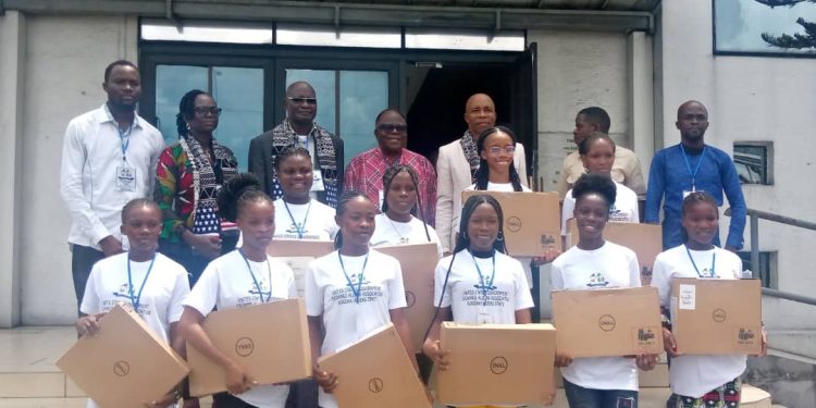 People standing out door. Ten of them (females) are holding a laptop pack in their hands