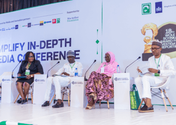 The image of 4 people seated on the stage in a panel discussion.