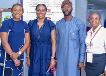 Four people standing, there is a man and three women, one woman is on clutches.