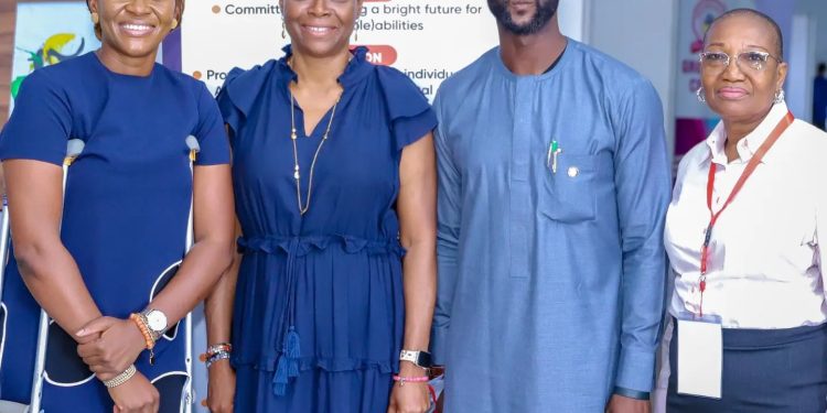 Four people standing, there is a man and three women, one woman is on clutches.