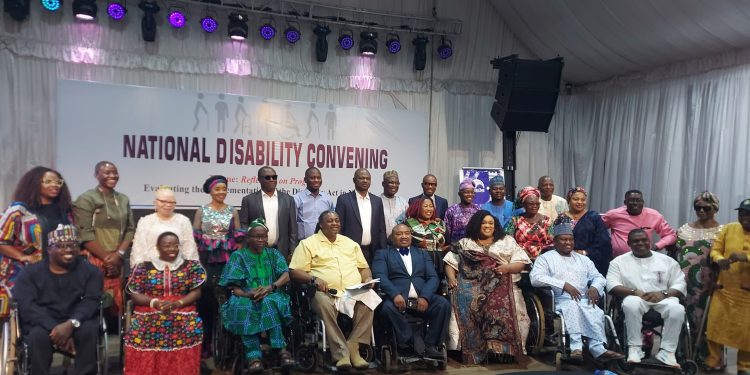 People standing indoor. Some are on seated on their wheel chairs