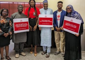Six people are standing indoor. three of them are holding placards in their hands