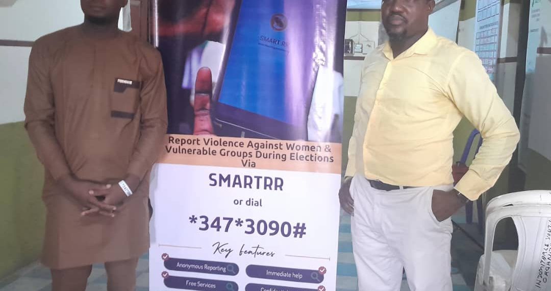 Two men standing indoor in front of a roll up banner