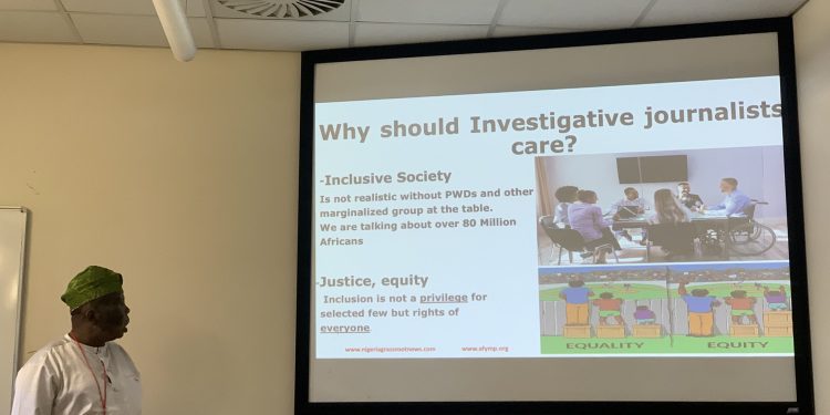 Yinka Olaito standing with the screen showing his presentation