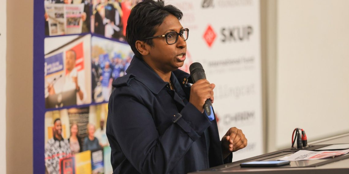 Dr Binesh holding a microphone and speaking to the audience