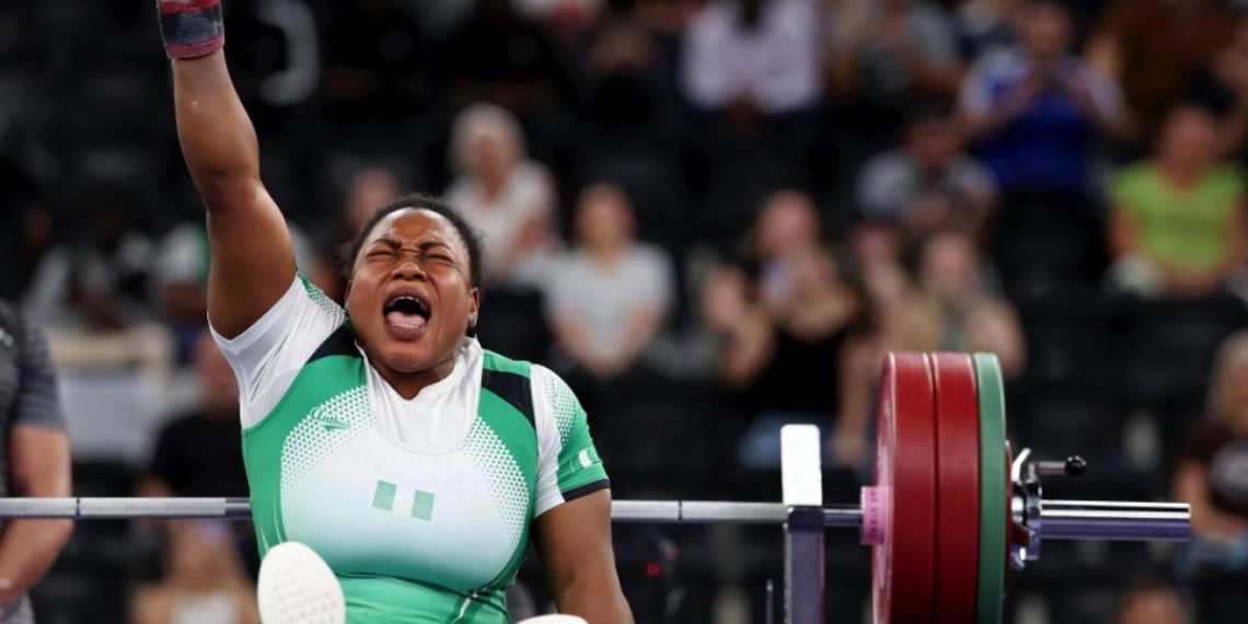 A woman sitting on a bench with one hand up