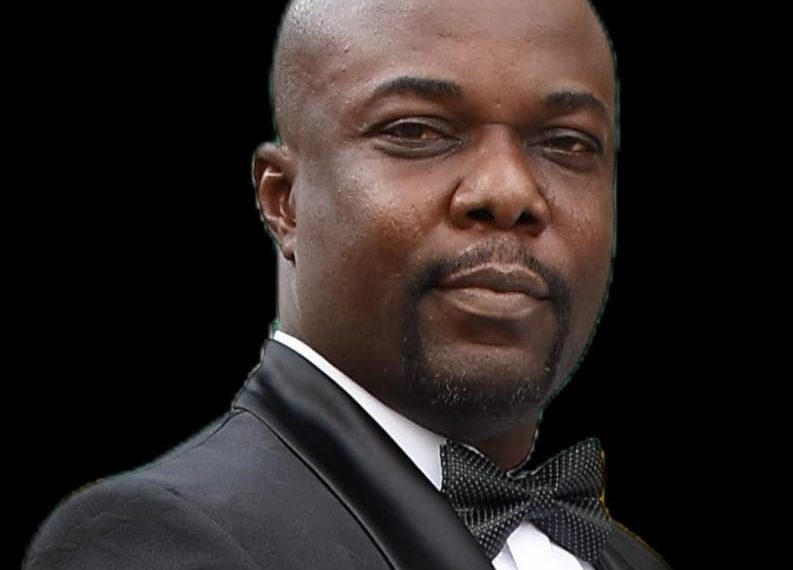 A man on balck suit with a black bow tie