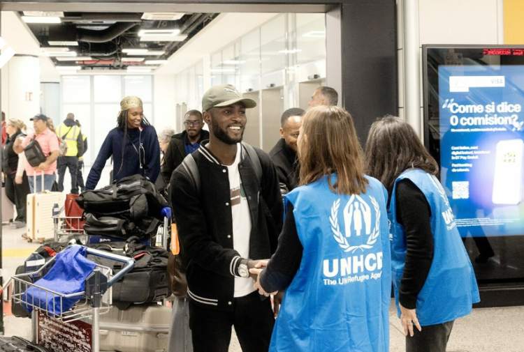 Group of people standing indoor. There are travelling bags behind them