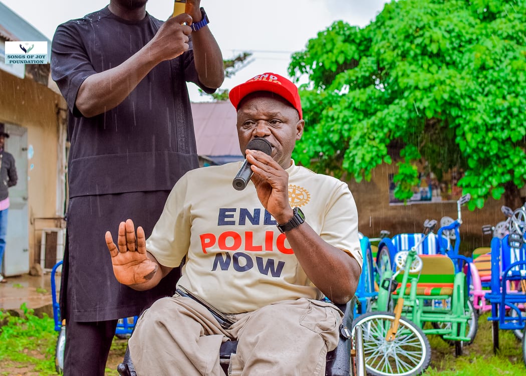 A man in wheelchair outdoor holding a microphone in left hand