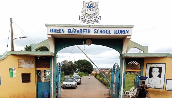 A wide opened gate. On the top of the gate is written Queen Elizabeth School Ilorin