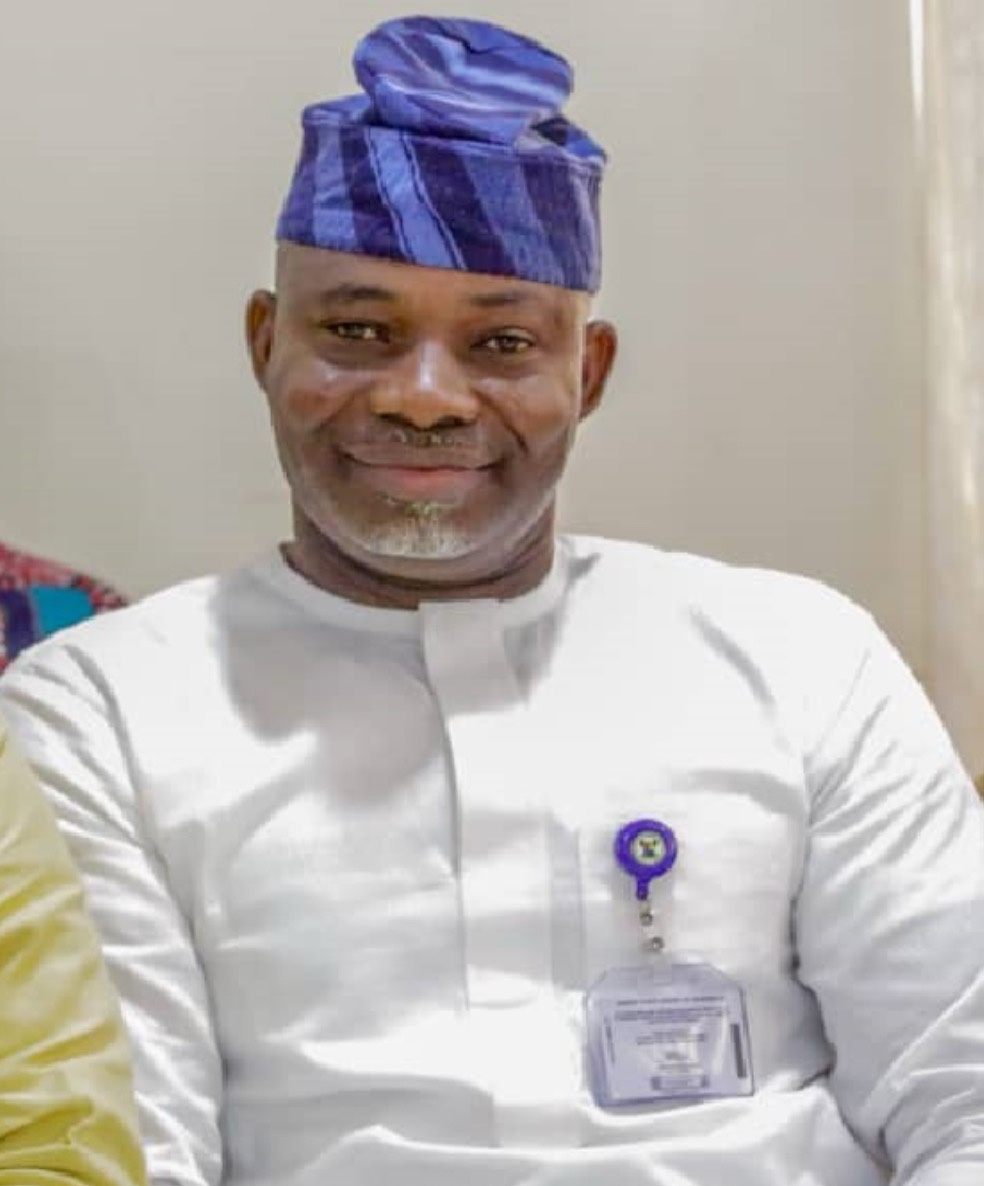 Belly to head shot of a man sitting indoor. The man is wearing a cap
