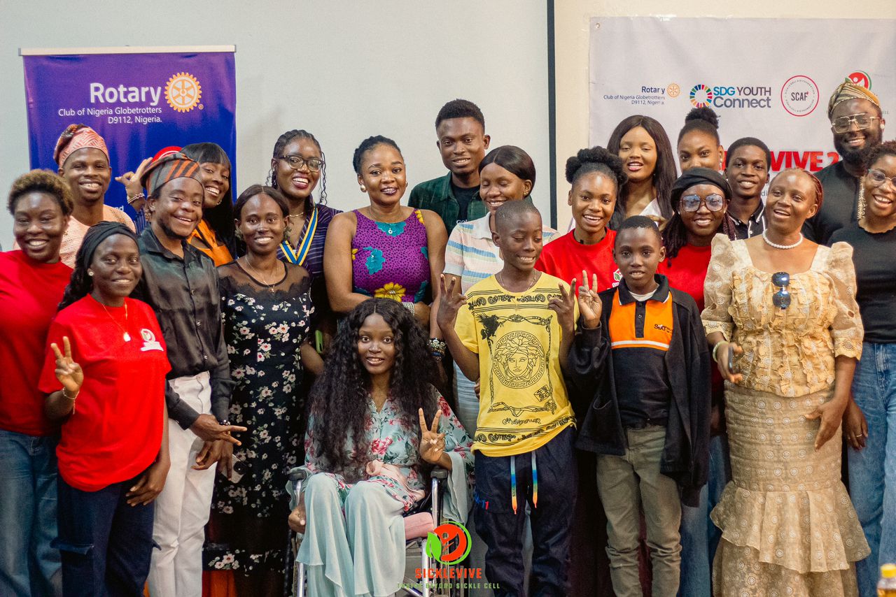 A group of people standing and a lady in a wheelchair indoors