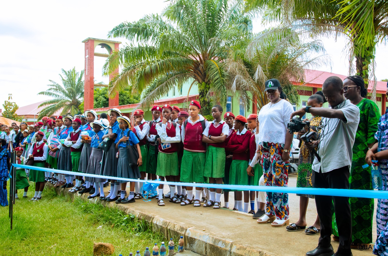 A group of people standing outdoors. Among them is a man holding a video camera.