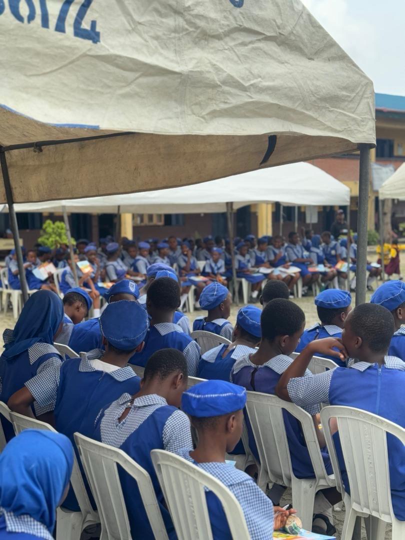 Many people (boys and girls) seated under a canopies