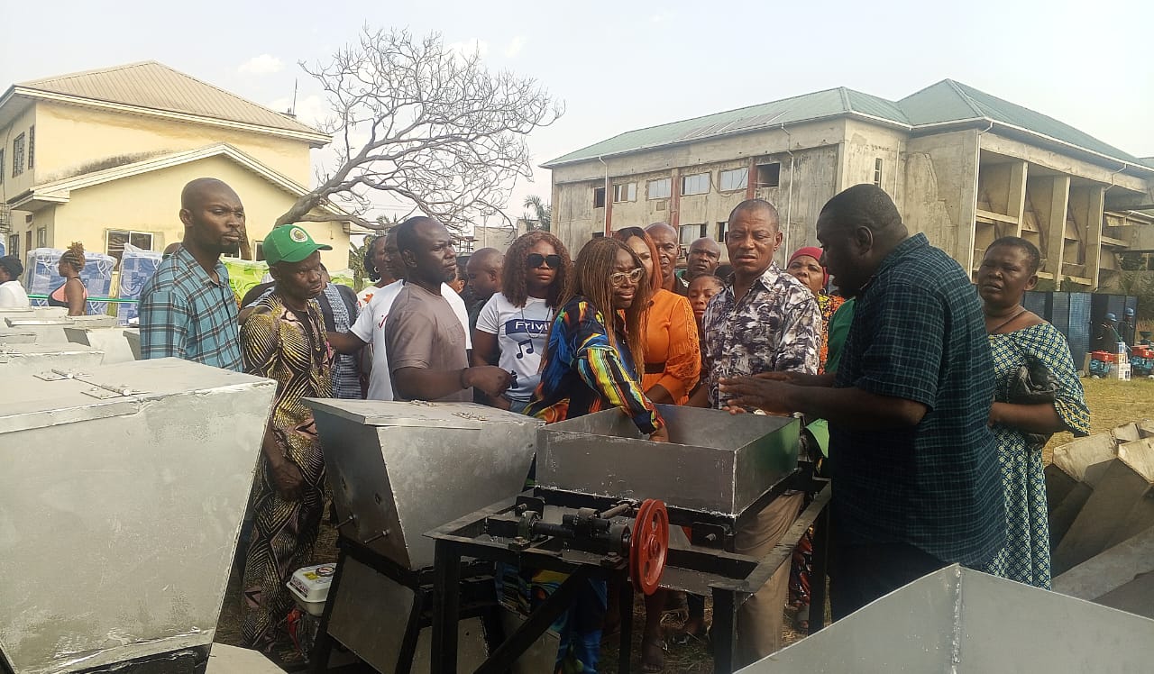 A group of people outdoors standing. In front of them is a metalic object