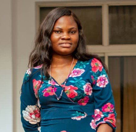Head to waist view of a woman standing outdoor.
