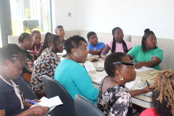 Women seated indoors in front of tables listening keenly