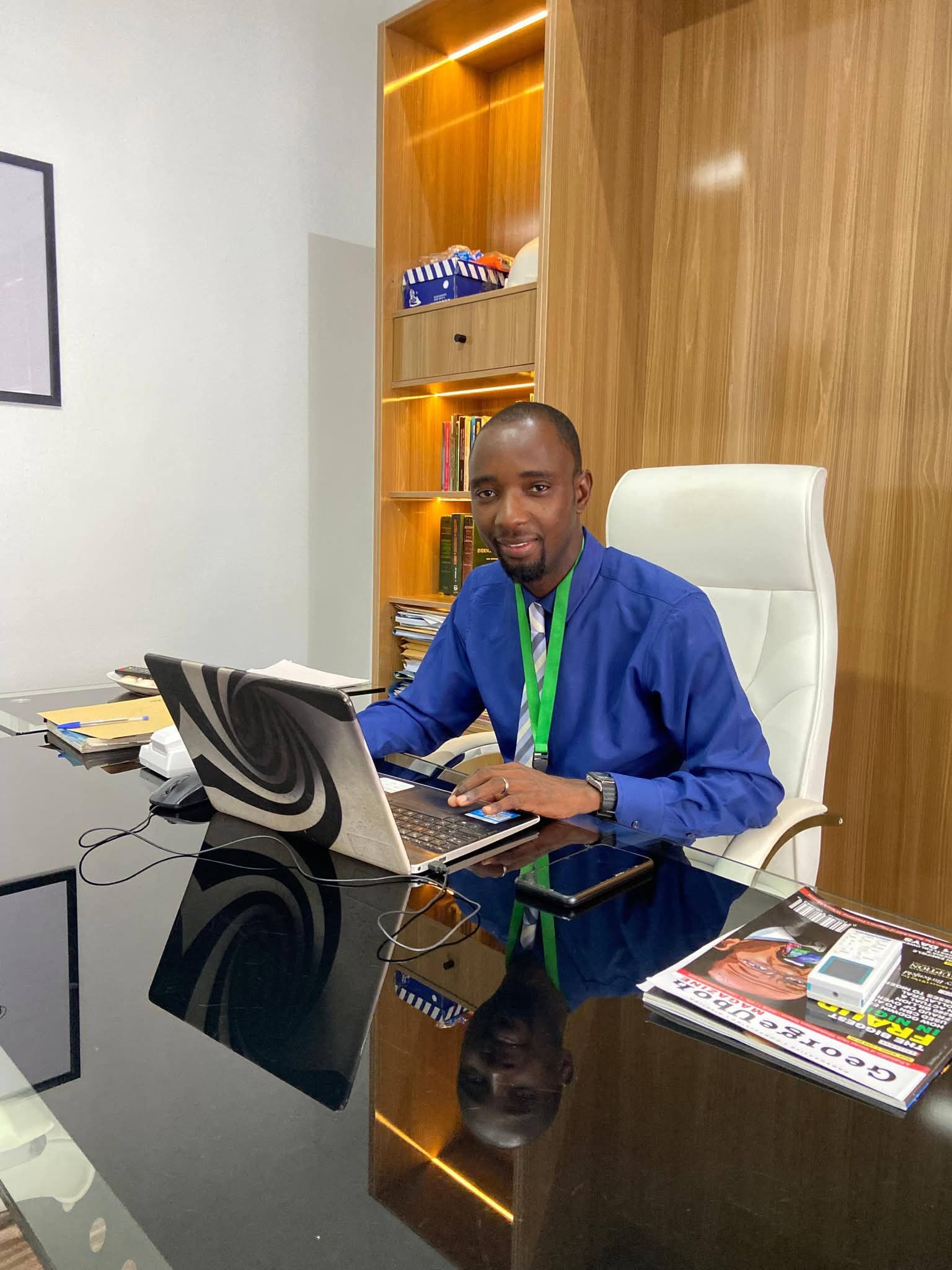 Stanley Ugabe sitting n a chair with a laptop in front of him on a table.