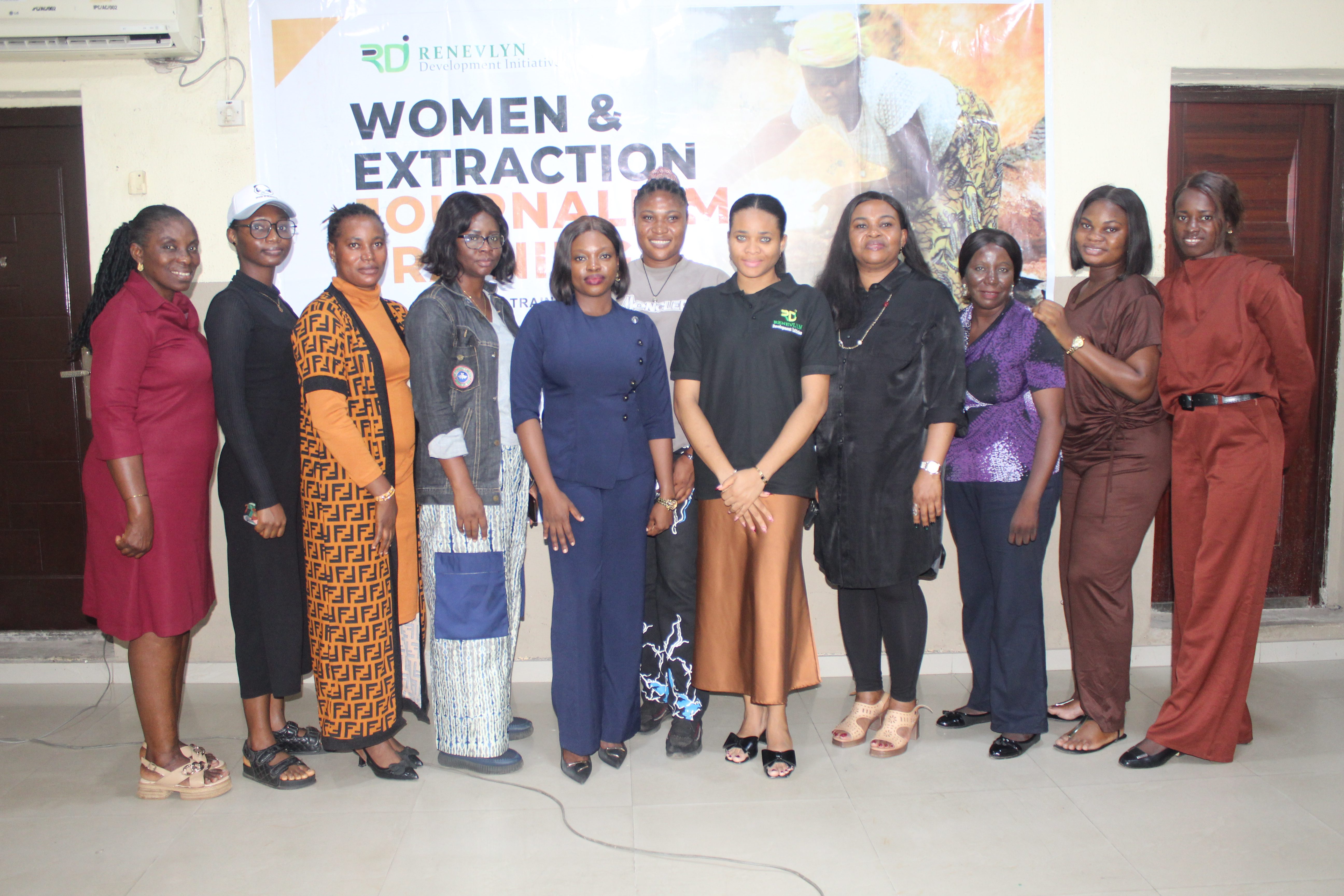 A group of women in a picture against a banner at a training on extractivism.