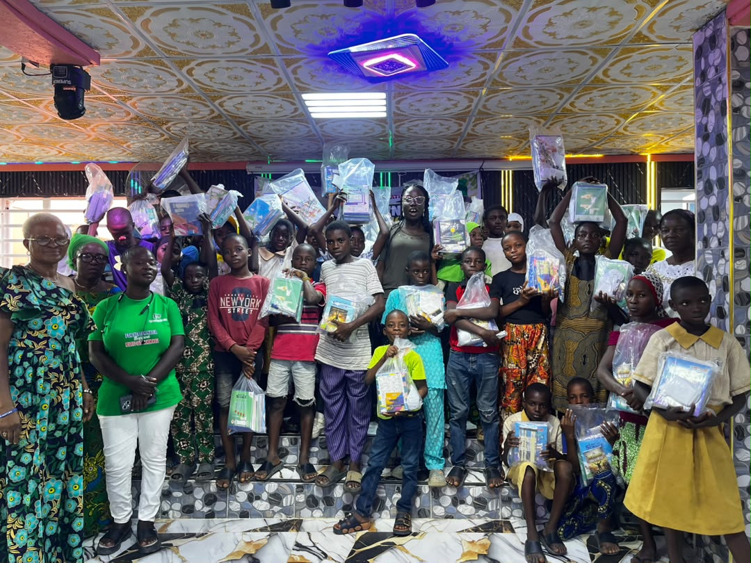 A group of chidren staning indoors with books in their hands