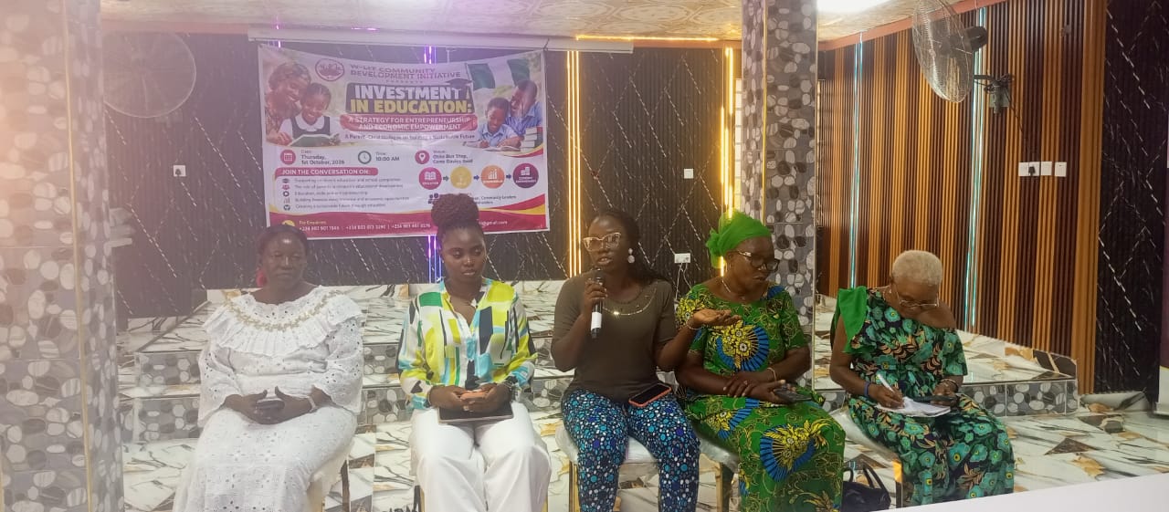 Five women sitting infoors. One is holding a microhpne in her hand